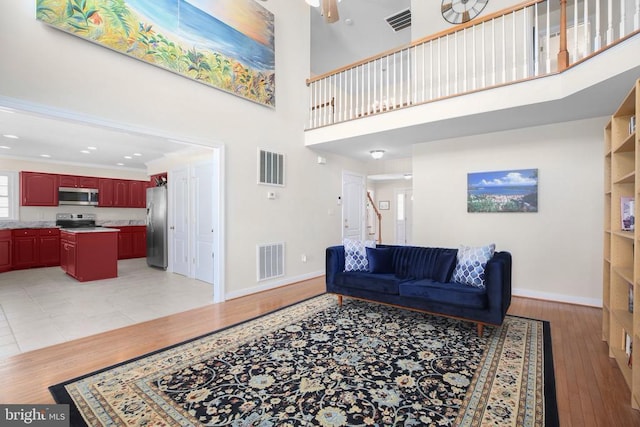 living room featuring baseboards, visible vents, and a towering ceiling