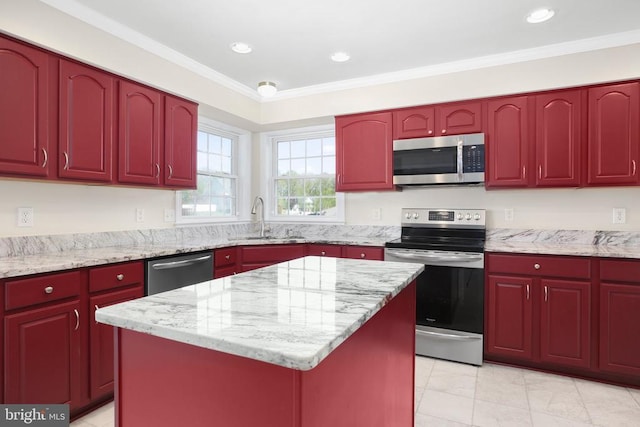 kitchen featuring stainless steel appliances, light stone counters, a kitchen island, and a sink