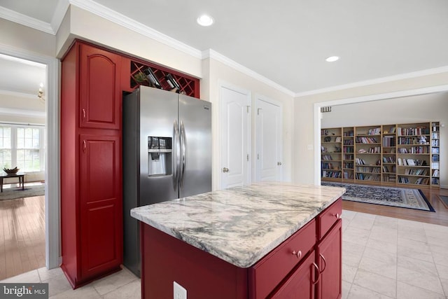 kitchen with stainless steel refrigerator with ice dispenser, dark brown cabinets, ornamental molding, and a center island