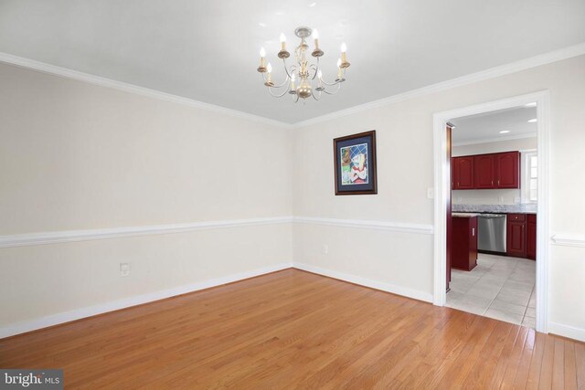 unfurnished dining area featuring ornamental molding, light wood-type flooring, a notable chandelier, and baseboards
