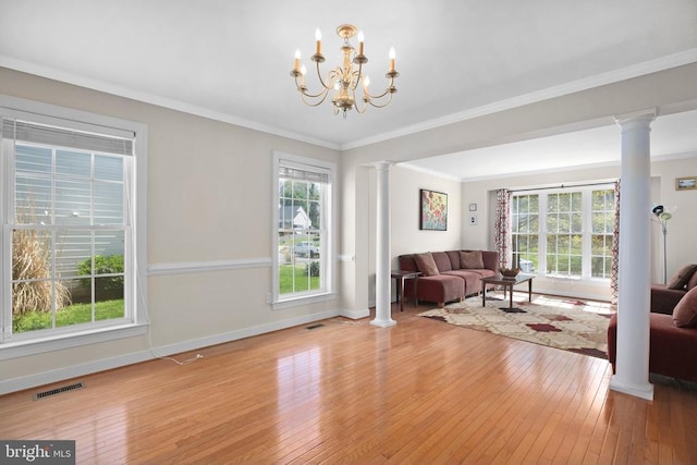living area with ornate columns, visible vents, hardwood / wood-style floors, and baseboards