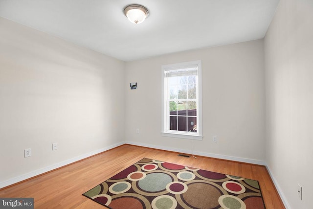 unfurnished room featuring visible vents, wood finished floors, and baseboards