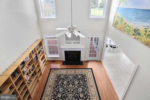 living room with wood finished floors, a wealth of natural light, ceiling fan, and a towering ceiling