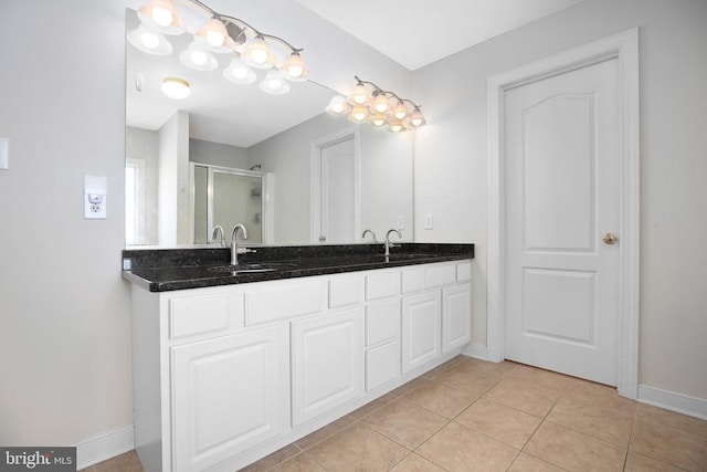 bathroom featuring tile patterned flooring, a sink, a shower stall, and baseboards