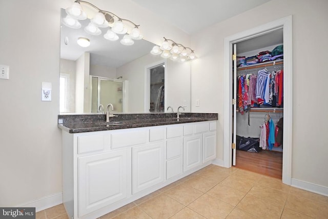 bathroom featuring tile patterned floors, baseboards, double vanity, and a sink