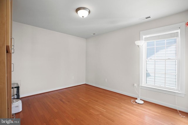unfurnished room with visible vents, wood finished floors, and baseboards
