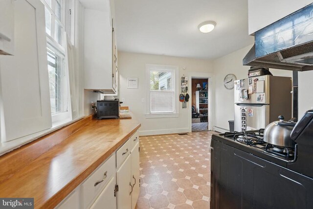 535 Winchester St, Warrenton, VA 20186 - kitchen featuring black gas stove, light floors, butcher block counters, white cabinetry, and freestanding refrigerator