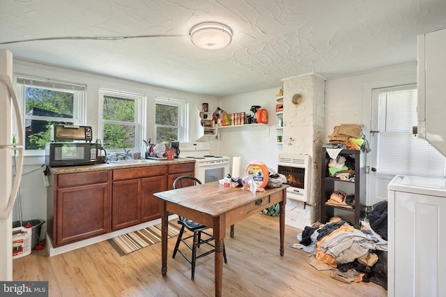 kitchen with brown cabinetry, heating unit, black microwave, white range with electric cooktop, and light wood-style floors