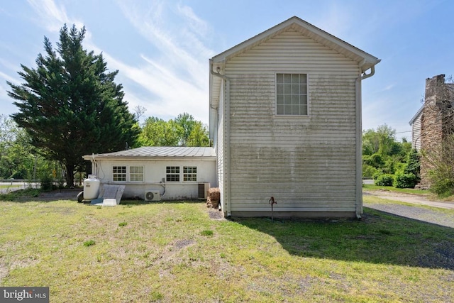 rear view of property featuring a yard and metal roof
