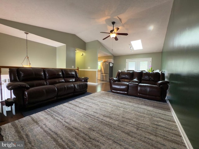  - living room with ceiling fan, vaulted ceiling, baseboards, wood finished floors, and a skylight