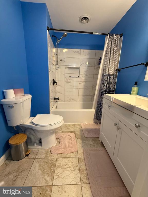  - full bathroom with toilet, shower / tub combo with curtain, vanity, and baseboards