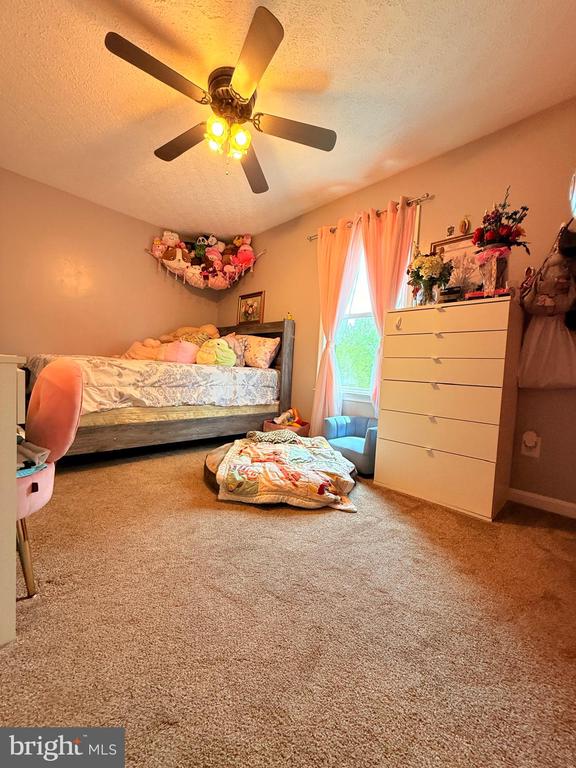  - bedroom with a textured ceiling, carpet, and a ceiling fan