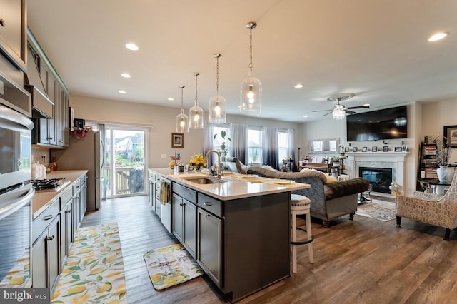 kitchen with a sink, recessed lighting, a kitchen bar, a ceiling fan, and an island with sink