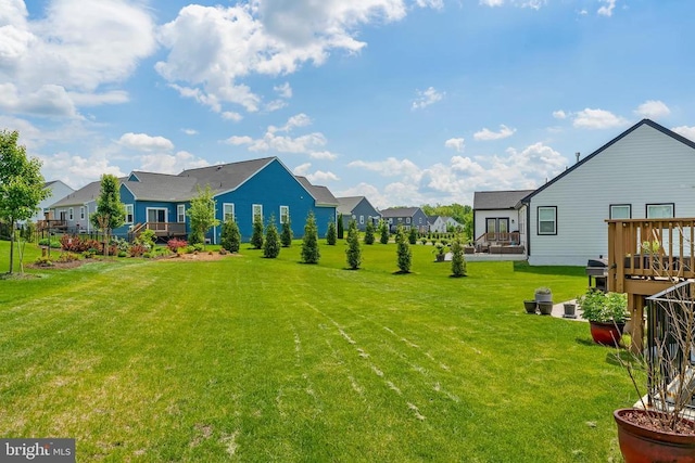 view of grassy yard with a residential view and a deck