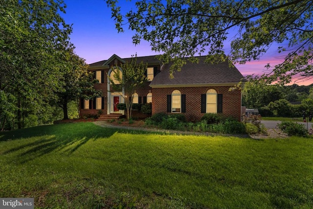 view of front facade featuring a front yard, brick siding, and roof with shingles