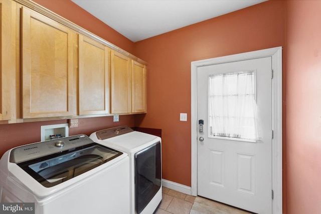 laundry area with independent washer and dryer, cabinet space, light tile patterned floors, and baseboards