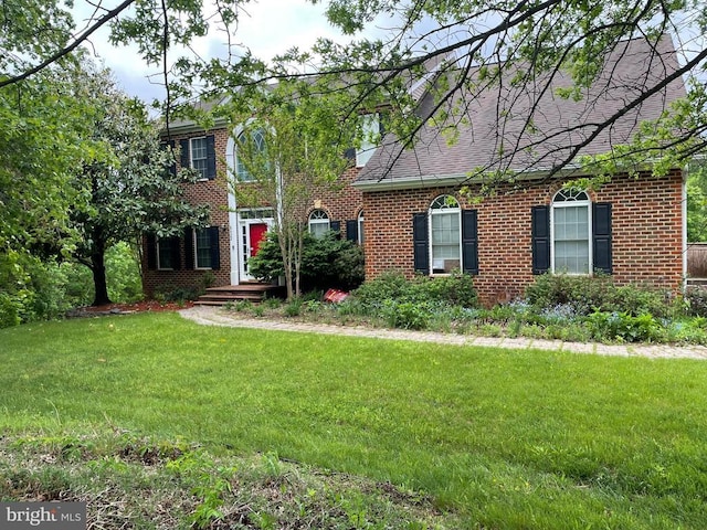 view of front of house featuring brick siding, a front yard, and a shingled roof
