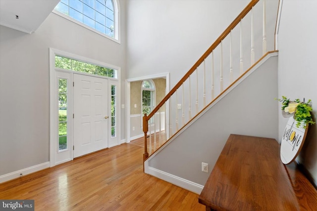 entrance foyer with stairs, a high ceiling, wood finished floors, and baseboards