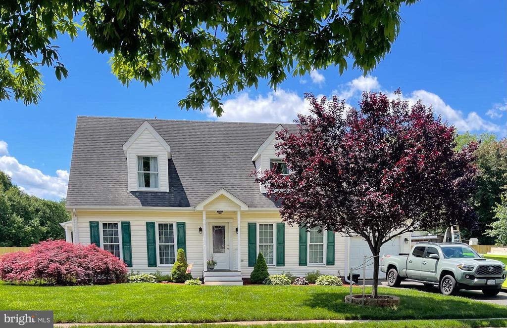  - new england style home featuring a front yard and a shingled roof