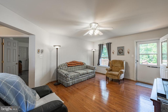 living room featuring wood finished floors, a ceiling fan, and baseboards