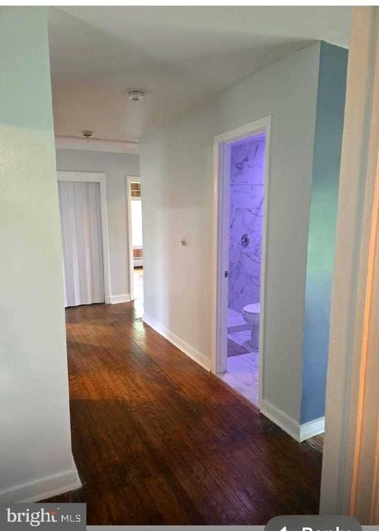 corridor with wood finished floors and baseboards