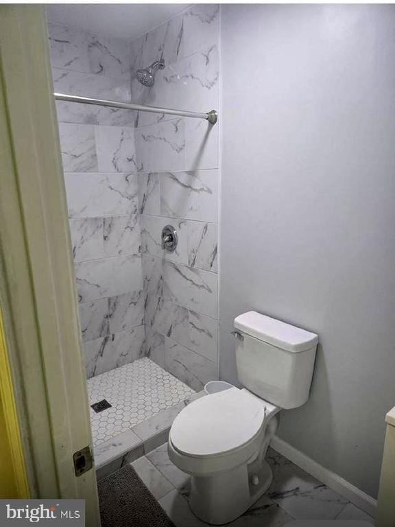 full bath with marble finish flooring, a shower stall, baseboards, and toilet