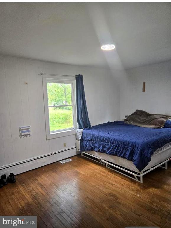 bedroom featuring wood finished floors and a baseboard radiator