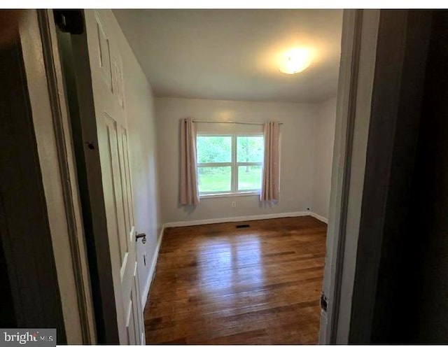 spare room featuring baseboards and wood finished floors