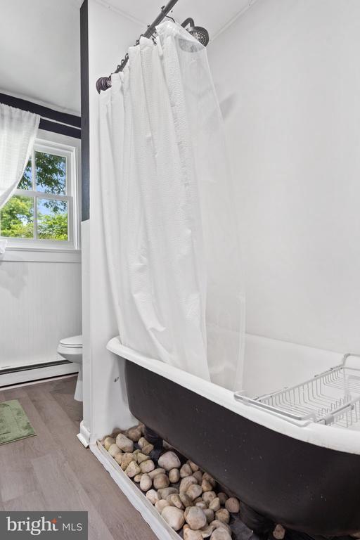 404 N Franklin St, Remington, VA 22734 - bathroom featuring wood finished floors, a baseboard radiator, and shower / bath combo with shower curtain