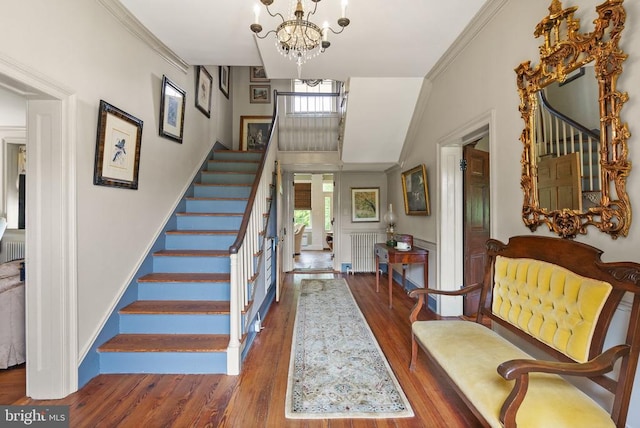  - foyer entrance with stairway, a chandelier, radiator heating unit, wood finished floors, and crown molding