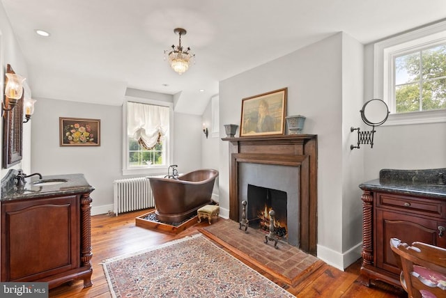  - full bath featuring radiator heating unit, a soaking tub, healthy amount of natural light, wood finished floors, and recessed lighting
