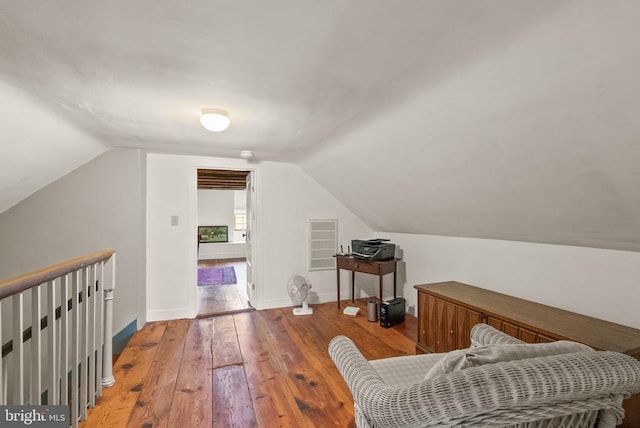  - living area with hardwood / wood-style floors, lofted ceiling, and an upstairs landing
