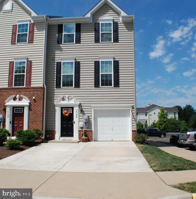 - view of front facade with brick siding, driveway, and an attached garage