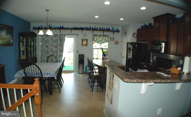  - kitchen featuring black appliances, dark countertops, recessed lighting, a kitchen breakfast bar, and a peninsula
