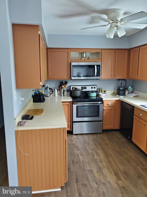  - kitchen with appliances with stainless steel finishes, wood finished floors, light countertops, and ceiling fan