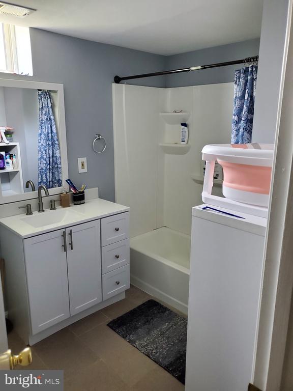  - full bath featuring washer / dryer, vanity, tile patterned floors, and shower / bath combo