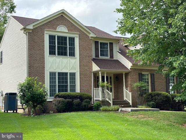 view of front facade with a front lawn, brick siding, and a porch