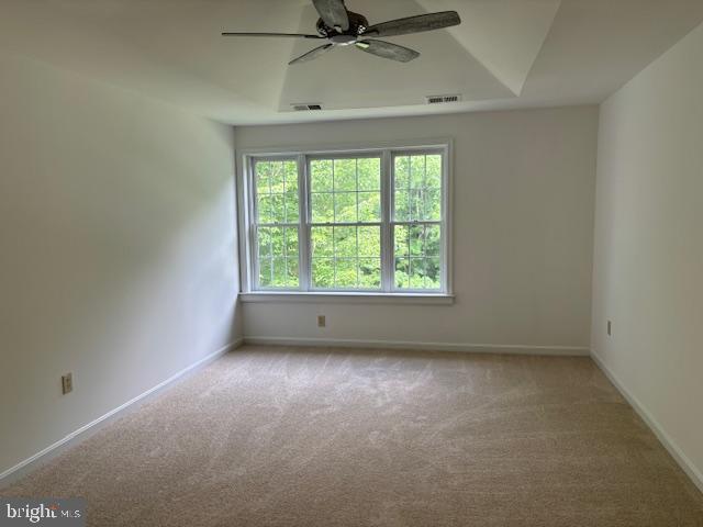 carpeted spare room with a ceiling fan and baseboards