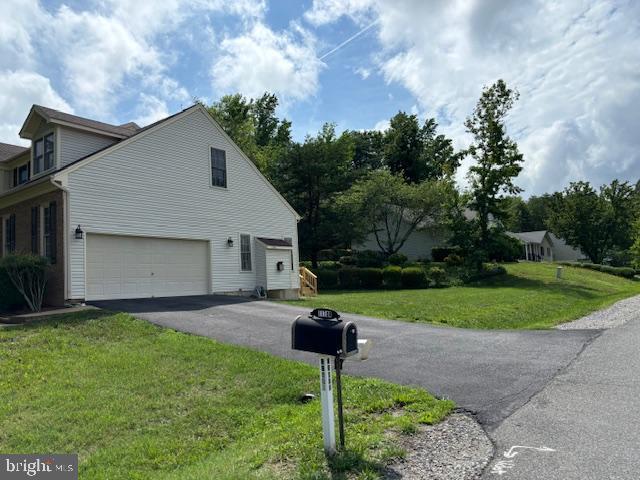 view of property exterior featuring asphalt driveway, a lawn, and an attached garage