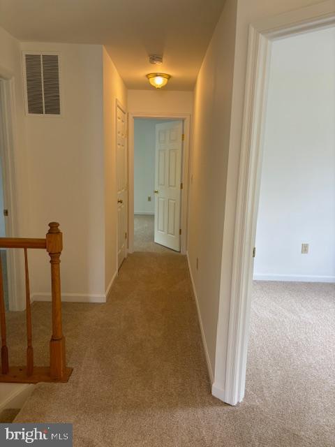 hallway featuring carpet flooring and baseboards