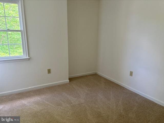 carpeted spare room featuring baseboards