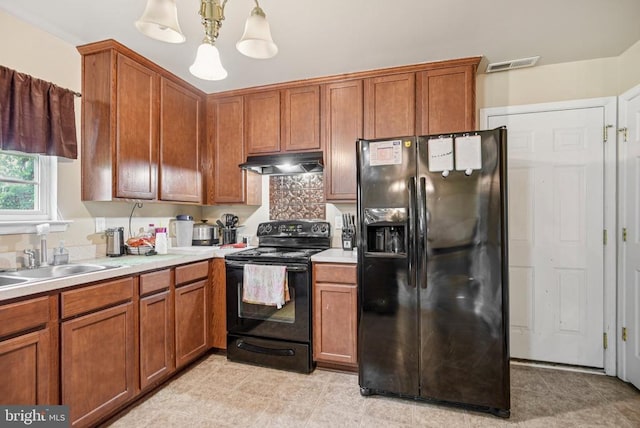  - kitchen with black appliances, under cabinet range hood, light countertops, and brown cabinets