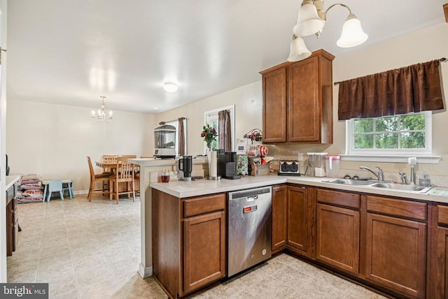  - kitchen featuring dishwasher, a chandelier, a peninsula, brown cabinetry, and light countertops