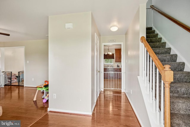  - corridor with wood finished floors, a chandelier, and stairway