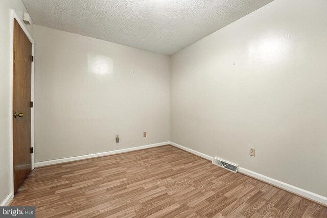  - empty room featuring light wood-style flooring and a textured ceiling