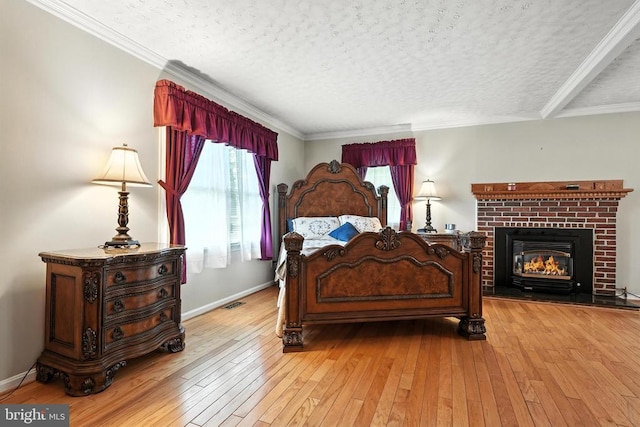  - bedroom featuring a textured ceiling, light wood-style floors, a fireplace, and crown molding
