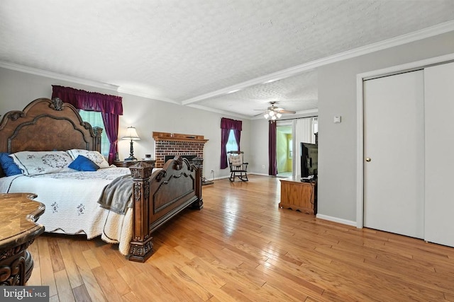  - bedroom featuring light wood-style flooring, a textured ceiling, a brick fireplace, and ornamental molding