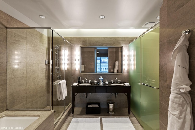 bathroom featuring tile walls, tile floors, a shower with shower door, and dual vanity