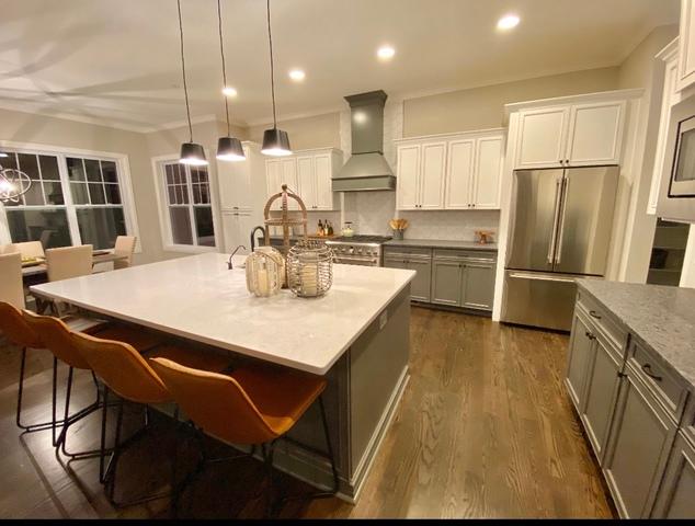 kitchen featuring dark hardwood / wood-style floors, an island with sink, high end appliances, custom exhaust hood, and a kitchen bar