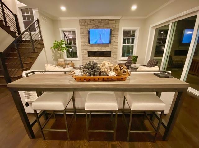 interior space featuring crown molding, a stone fireplace, and dark hardwood / wood-style floors